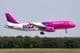 Wizz air repülő alacsony magasságban repül, háttérben egy erdő látható. 