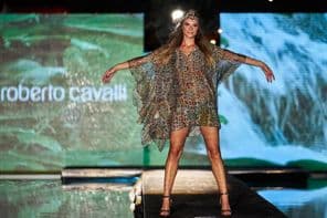 Roberto Cavalli felirat kijelzőn a háttérben, előtte a kifutón egy női alak Roberto Cavalli ruhában.