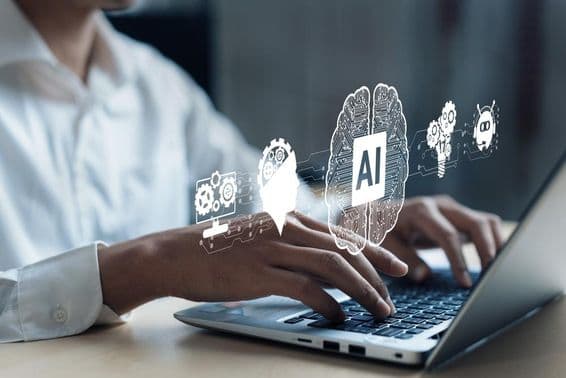 Egy notebook felett kivetitve kép egy mesterséges AL agyról és más dolgokról. Emberi kéz dolgozik a gépen.