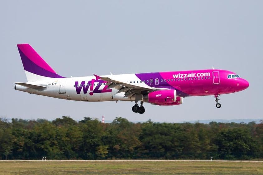 Wizz air repülő alacsony magasságban repül, mögötte erdő látható.