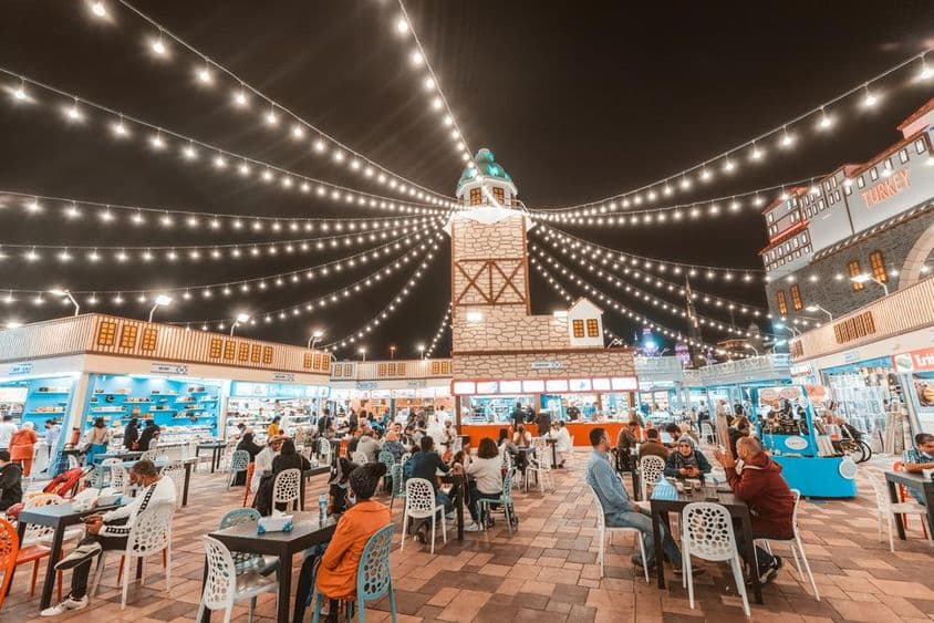 Global Village , asztaloknál ülnek turisták es helyiek, ételkülönlegességeket kóstoltak meg.