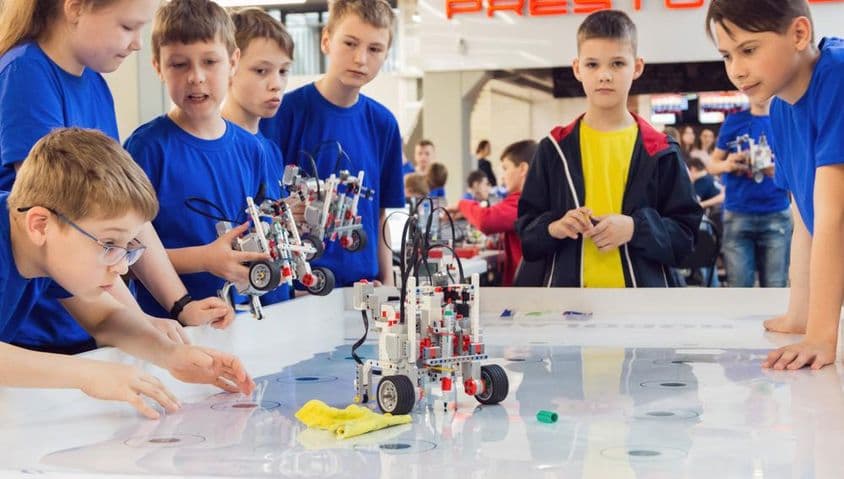 Diákok kék polóban, robotot építenek és programoznak.