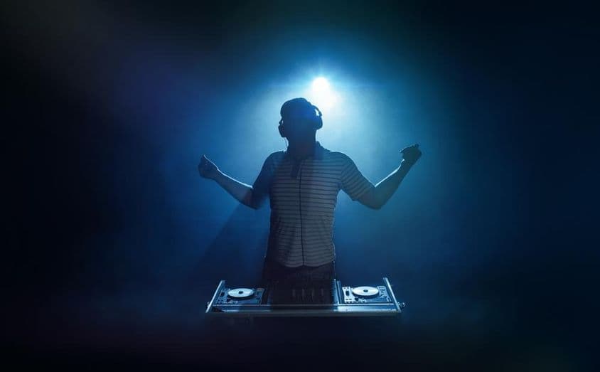 Egy ember áll a dj pult mögött.