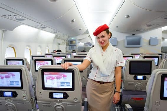 Emirates repülőgép belseje, előtérbe egy légi utaskisérő.