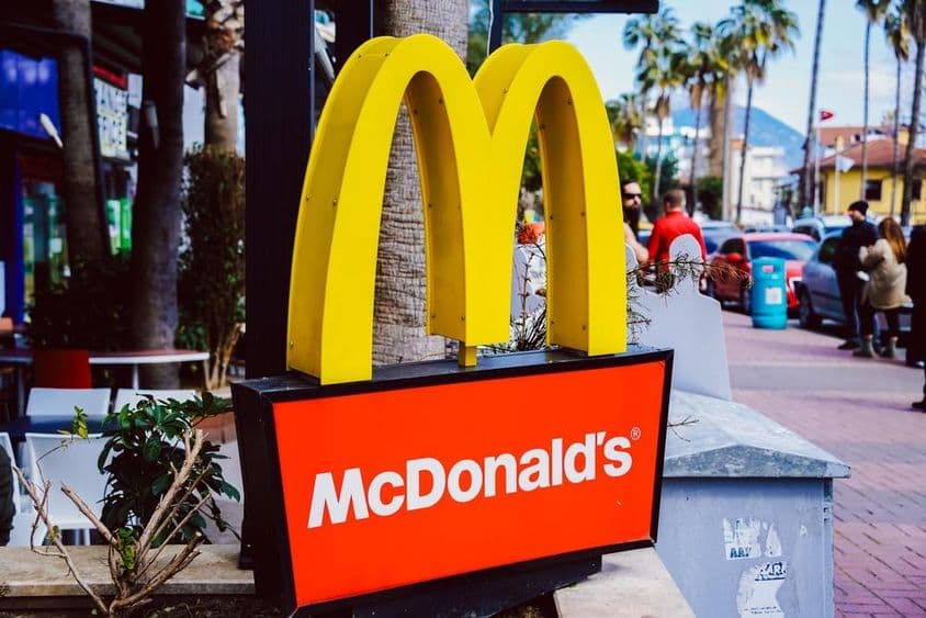 McDonalds táblája látható háttérben egy utca képpel.