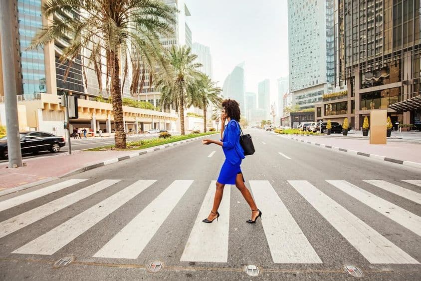 Dubaiban egy nő megy át a zebrán egy kihalt úton, mögötte házakat látni.