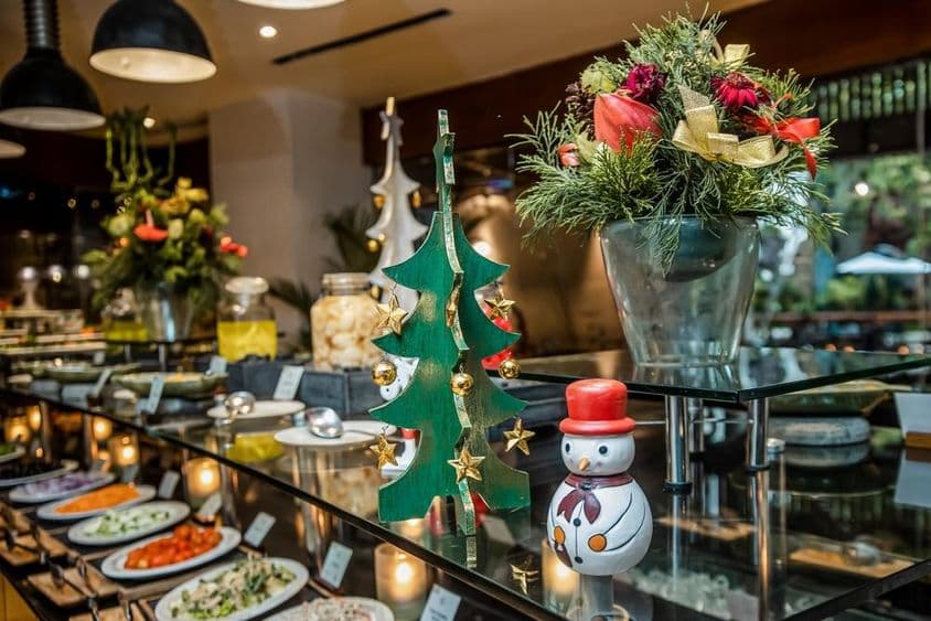 Kis hoepmber van egy étterembe a zöldséges pult tetején, mellette karácsonyfa fából.