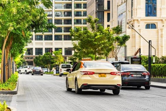 Dubai autók az úton, előtérben egy taxi, mögötte házak.