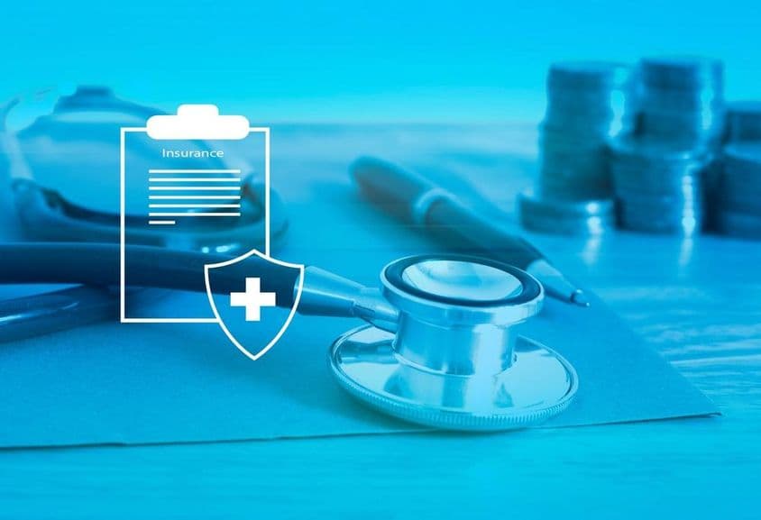 Egészségbiztosítás előtérben, hátul sztetoszkóp és egy kis apró.