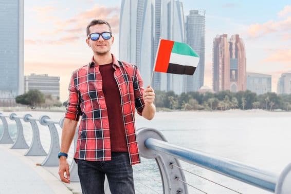 Fiatalember Dubaiban a Marinán egy UAE zászlóval.