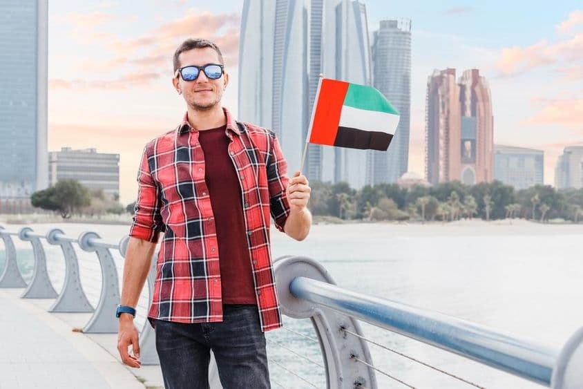 Fiatalember Dubaiban a Marinán egy UAE zászlóval.