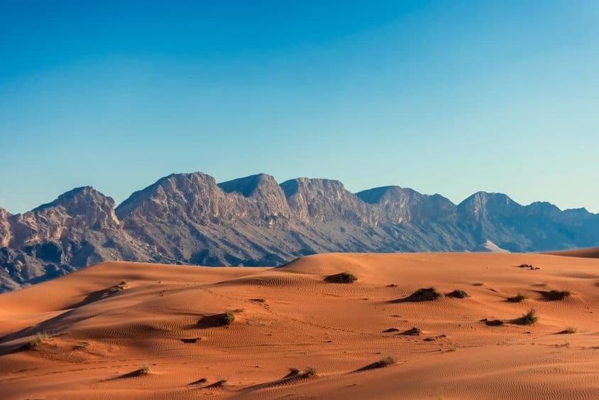 UAE sivatag, háttérben hegyekkel.