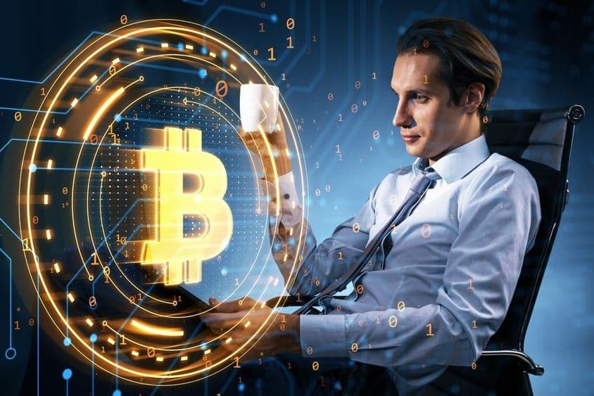 Üzletember kávésbögrével a kezében néz a bitcoin árfolyamot.