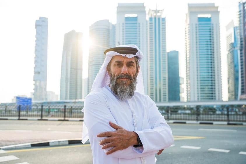 Öreg dubai férfi mögötte a felhőkarcolokkal.