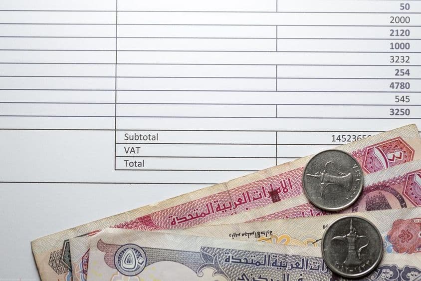 Dirham papírpénzek, kevés apró, adóelszámolás egy kinyomtatott papíron.