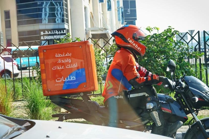 Motoros ételkiszállítók munkájuk közben az utcán.
