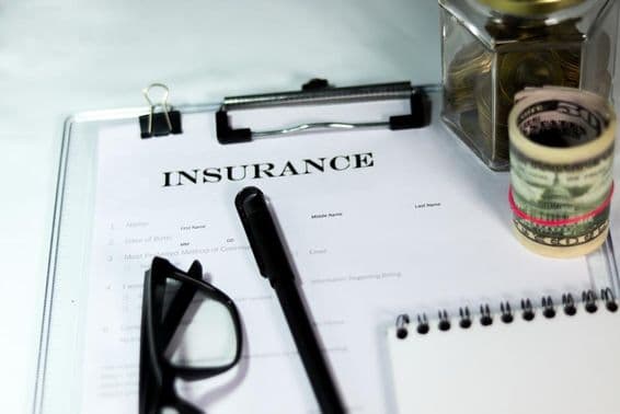 Biztosítási űrlap érmés doboz és dollárköteg tollal és szemüveggel.