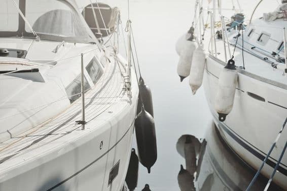 Fehér, modern vitorlás egy mólóhoz kikötve egy jachtkikötőben.