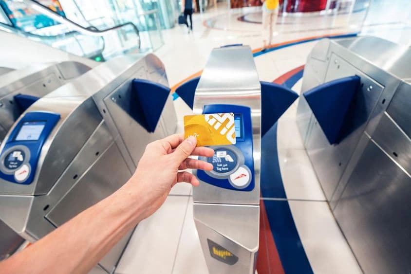 A férfi utas arany NOL kártyát használ a dubaji metróban a forgóajtón való áthaladáshoz és az első kocsiban való utazáshoz.