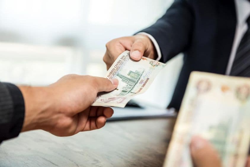 Üzletember pénzt ad, Egyesült Arab Emírségek dirham pénznemben, a partnerének.