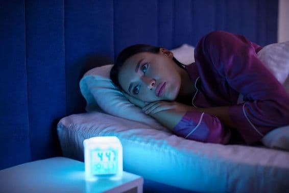 Szomorú álmatlan nő fekszik az ágyban, és néz el, nem tud aludni, álmatlanságban szenved.