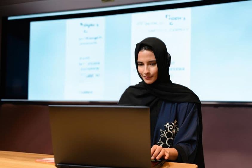 Tanárnő visel Abaya Hijab kivetítő képernyővel háttérként, modern osztályterem digitális képernyővel.