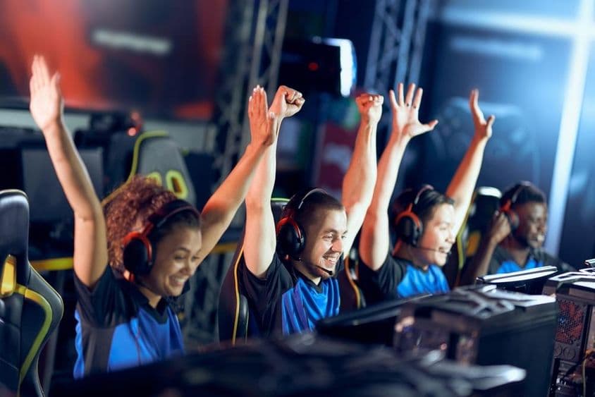 Boldog kiber sport játékosok csapata ünnepli a sikert, miközben részt vesznek az eSport versenyen.