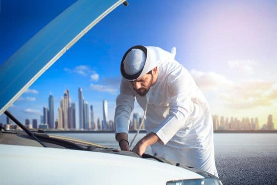 Egy arab férfi ellenőrzi autóját, motorház nyitva.