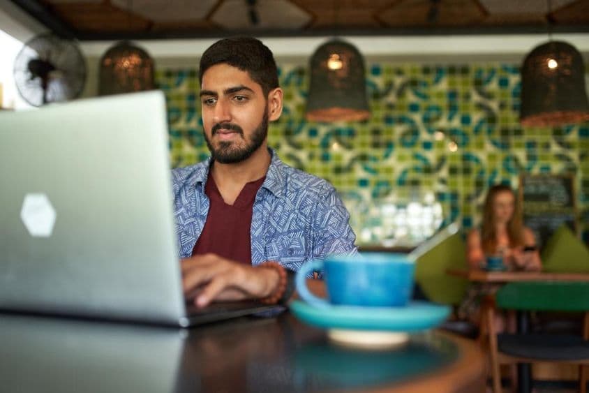 Indiai férfi dolgozik a divatos coworking térben.