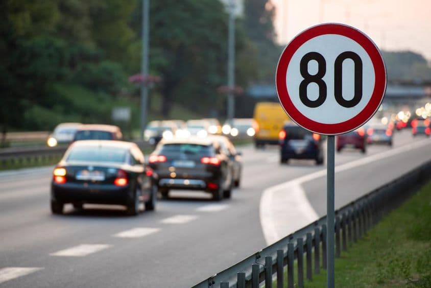 80km/h Sebességkorlátozó tábla egy autóval teli úton.