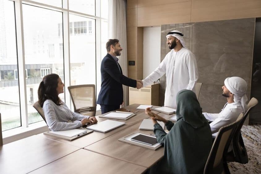 Arab és európai üzletemberek kezet ráznak a csapattalálkozón, céges megbeszélésen.