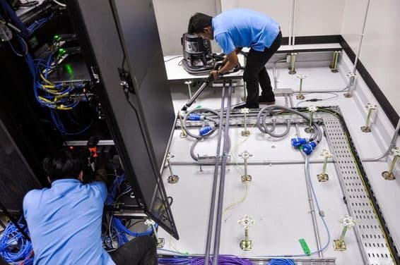 Szervertermet építenek munkások, állpadló és rack szekrény.