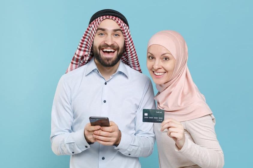 Mosolygó pár hitelkártyát és telefont tart a kezében.