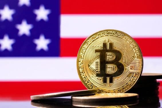 Arany Bitcoin fém érme a háttérben az USA zászlaja.