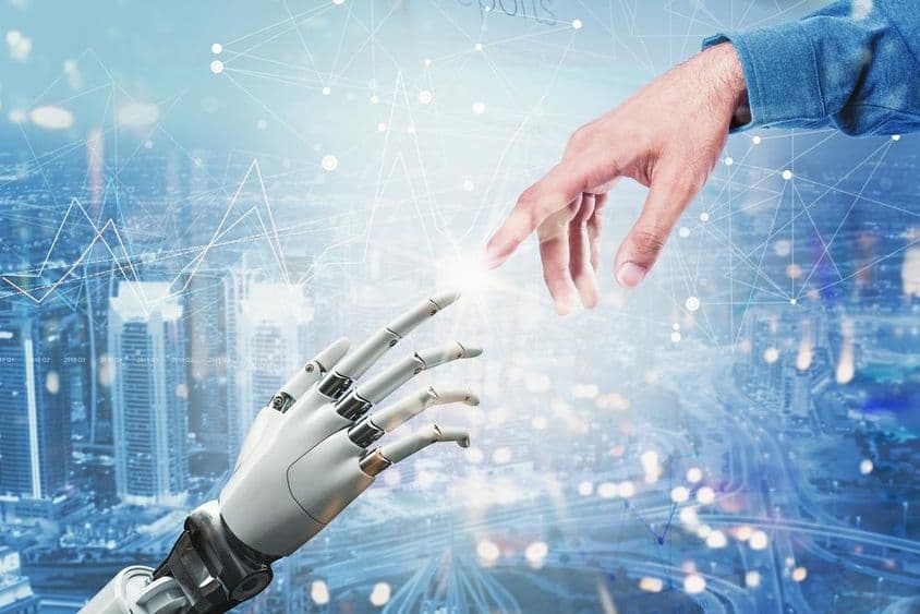 3D-s robot keze és emberi keze találkozik futurisztikus városi háttér felett.