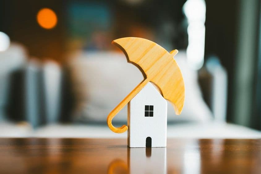 Modell esernyő egy fából készült házon, házbiztosítás.