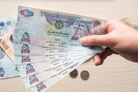 Egy lány a kezében 500-as Egyesült Arab Emírségek dirham bankjegyeket, papírpénzt tart.