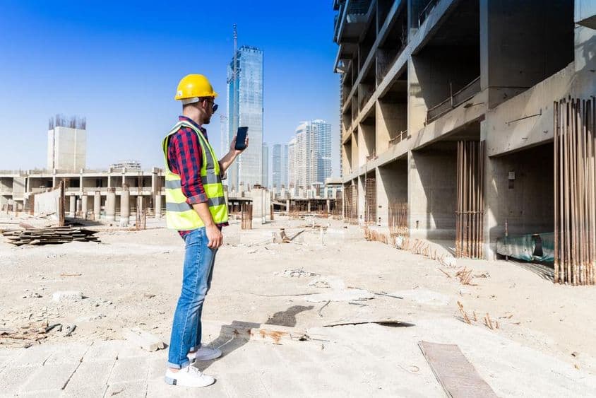 Okostelefon, védősisak és hi-vis kabát, dubai látképe alatt, építőmunkás.