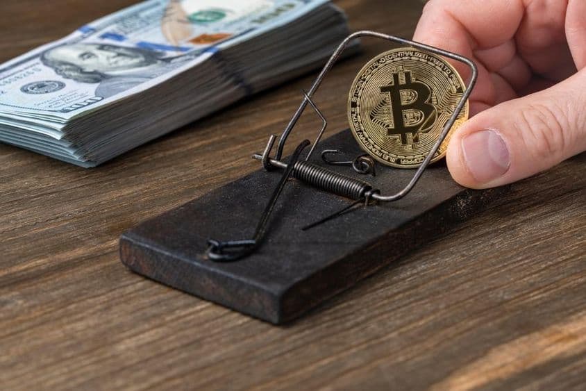 Kriptovaluta érmék bitcoint egérfogóban, csapdába esve 100 amerikai dollár bankjegyekkel.