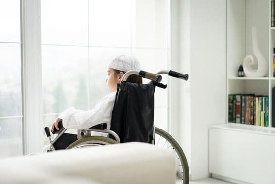 A tolószékben ülő kisfiú ablakon keresztül néz.