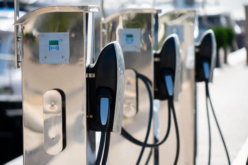 Elektromos autó töltőállomás luxuskikötőben a tenger mellett.