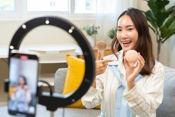 Influencer fiatal nő blogger okostelefont használva beszél video streaming podcaston.