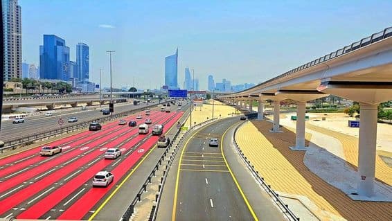 Dubaiban, az út pirosra van festve, fehér sávjelzéssel és 100 km h-t jelző sebességkorlátozó táblákkal.