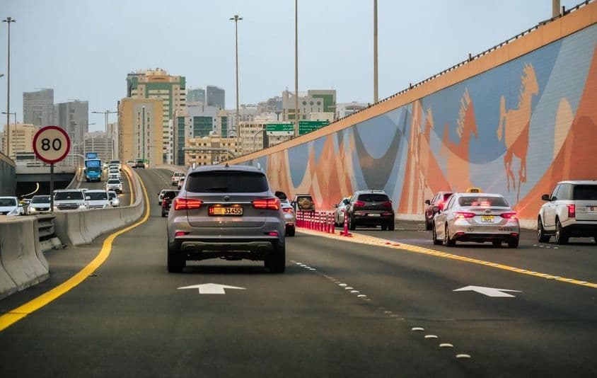 Autóforgalom egy autópálya úton felhőkarcolók épülete a háttérben az Egyesült Arab Emírségekben Dubaiban.