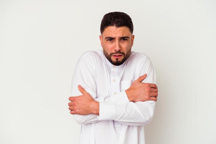 Fiatal arab férfi tipikus arab ruhában didereg a hideg miatt.