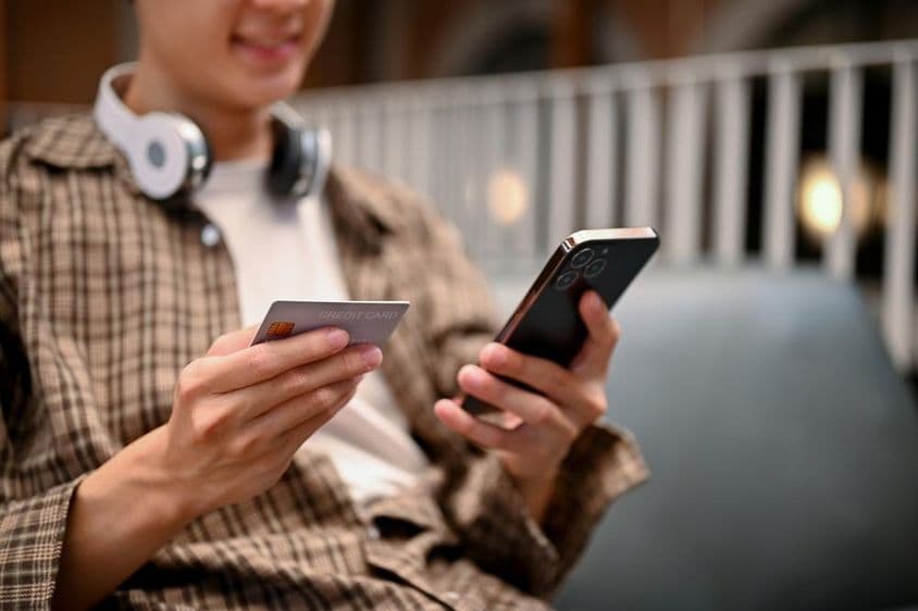 Egy ázsiai férfi, aki hitelkártyás fizetési szolgáltatást használ az online vásárlási alkalmazásba.