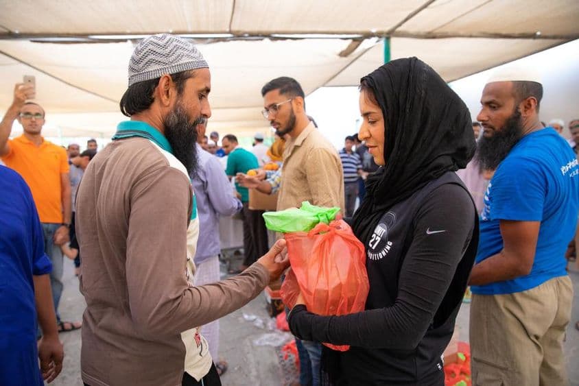 Önkéntesek élelmiszercsomagokat osztanak ki a dolgozóknak iftar étkezés közben.