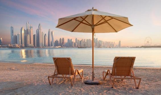 Gyönyörű strand Dubaiban 2 napozószékkel és egy napernyővel.