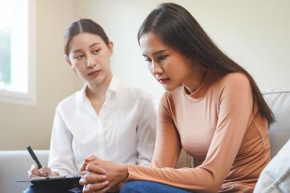 Szomorú ázsiai fiatal nő, pszichológussal konzultál.