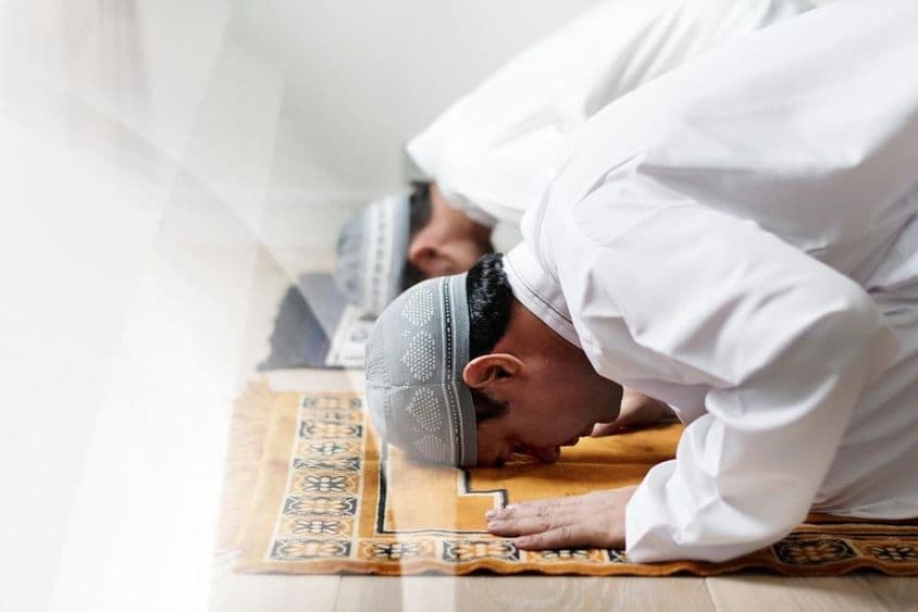 A fehérbe öltözött iszlám férfiak imára hajolnak.